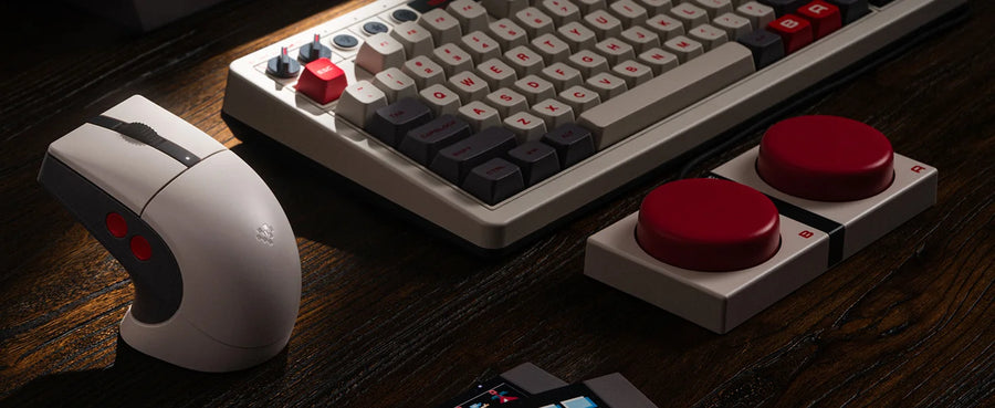 Maus 8BitDo Retro R8 N Edition auf einem Schreibtisch neben einer mechanischen Retro-Tastatur