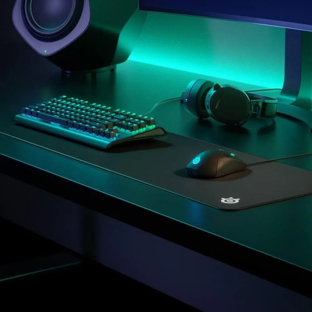 SteelSeries QcK Edge XL gaming mouse pad on a sleek gaming desk with keyboard and headphones.