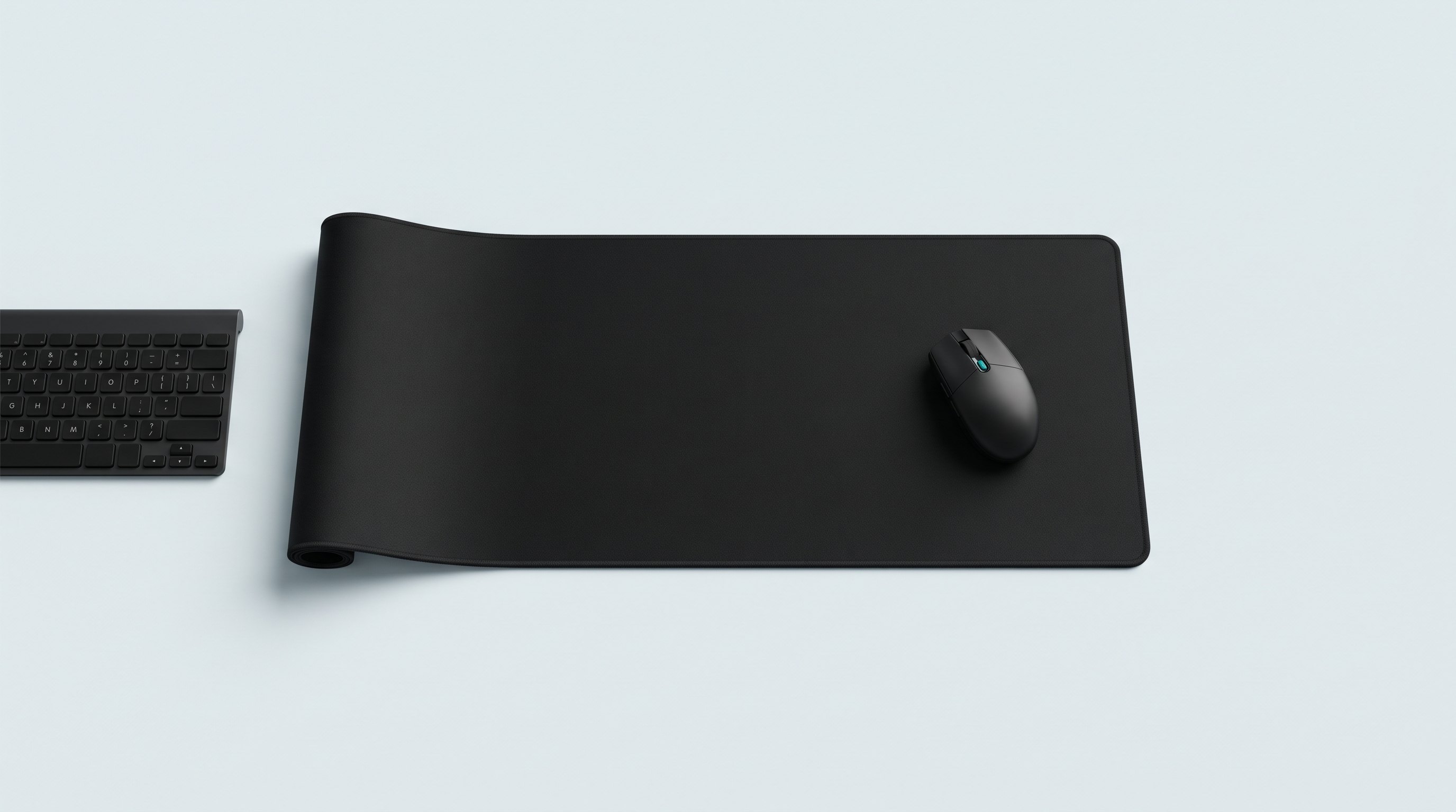 Très large tapis de bureau en tissu noir déroulé, avec une souris et le bord d'un clavier