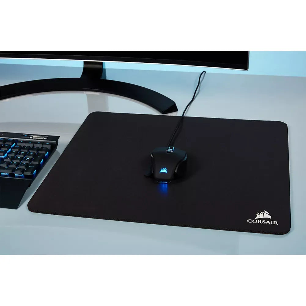 Corsair MM100 Taille M gaming mouse pad with a wired mouse and keyboard on a desk.