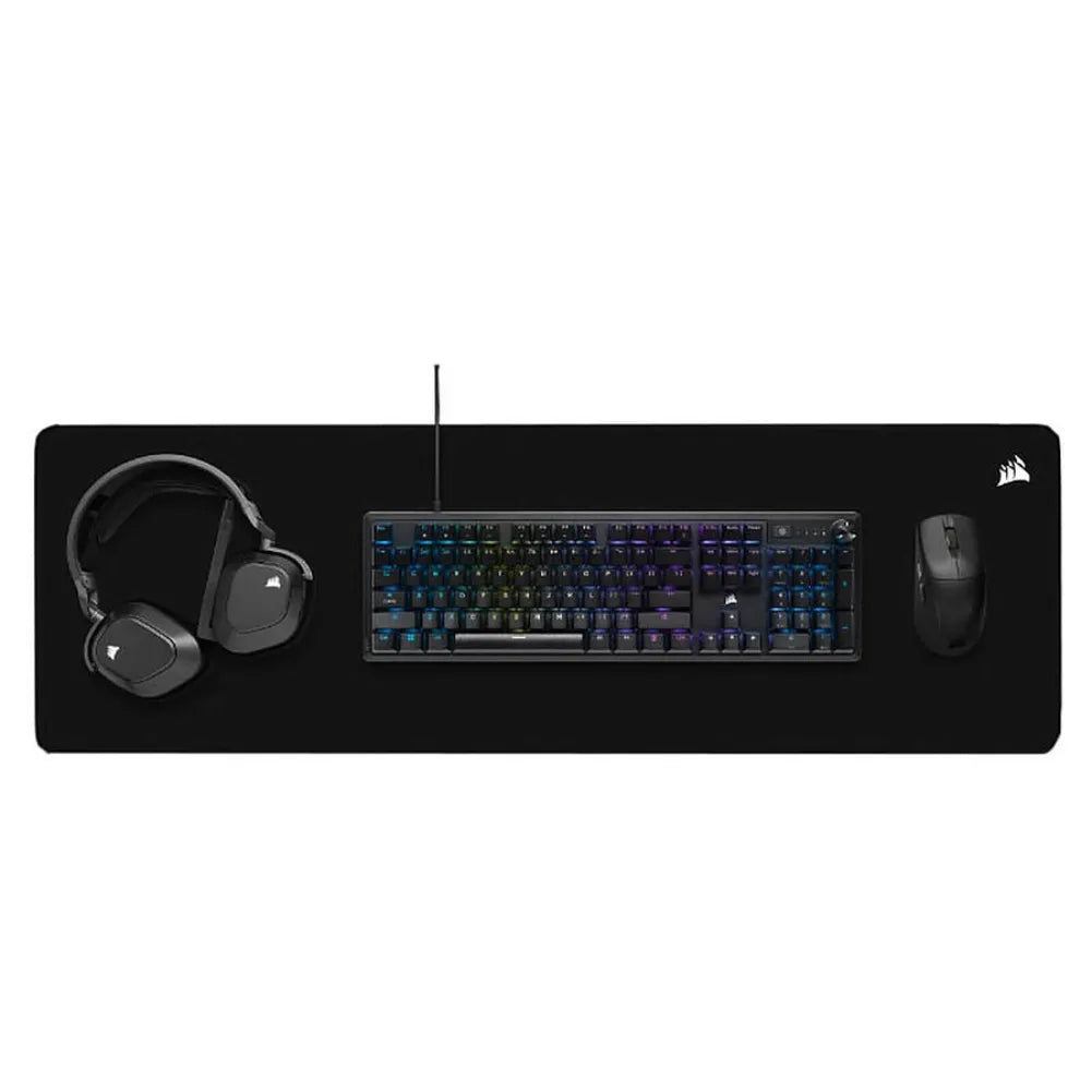 Corsair MM5000 V2 XXL gaming mouse pad with mechanical keyboard, gaming mouse, and headset on a black surface.