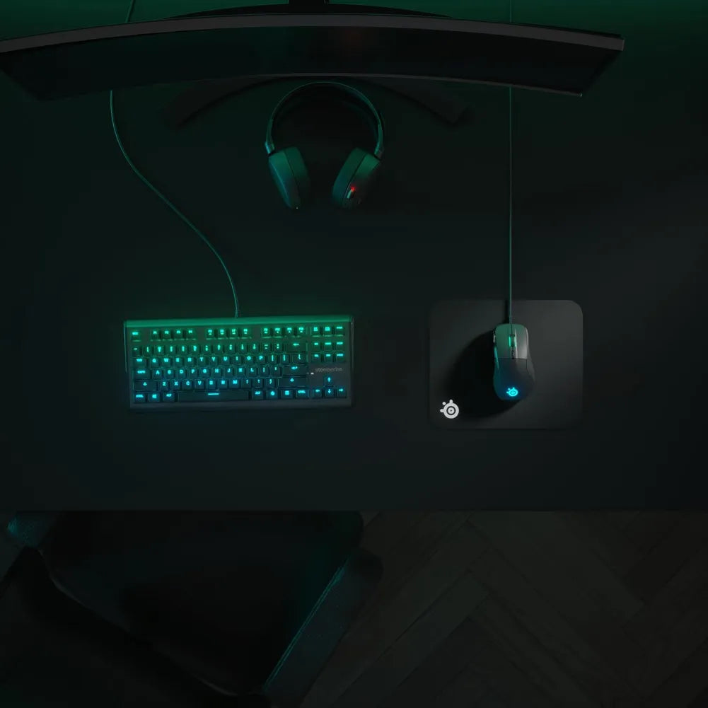 Bureau de jeu avec clavier rétroéclairé en vert, casque de jeu et tapis de souris SteelSeries QcK Mini.